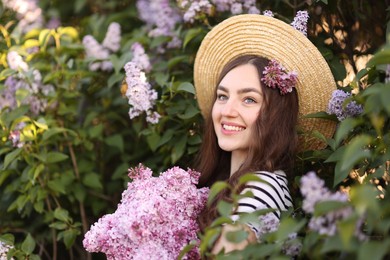 Photo of Smiling woman among lilac flowers and leaves outdoors