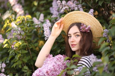 Photo of Beautiful woman among lilac flowers and leaves outdoors