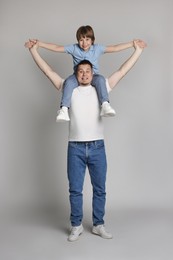 Photo of Father and his son having fun together on grey background
