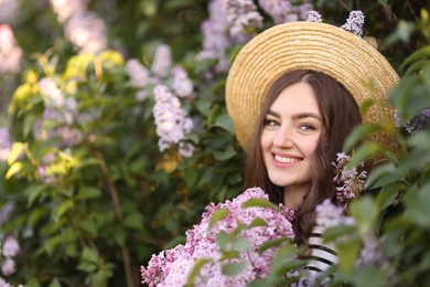 Photo of Smiling woman among lilac flowers and leaves outdoors. Space for text