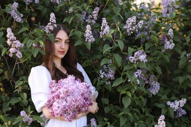 Photo of Beautiful woman among lilac flowers and leaves outdoors