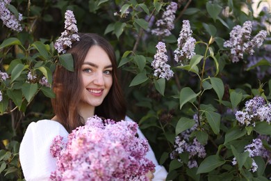 Photo of Smiling woman among lilac flowers and leaves outdoors