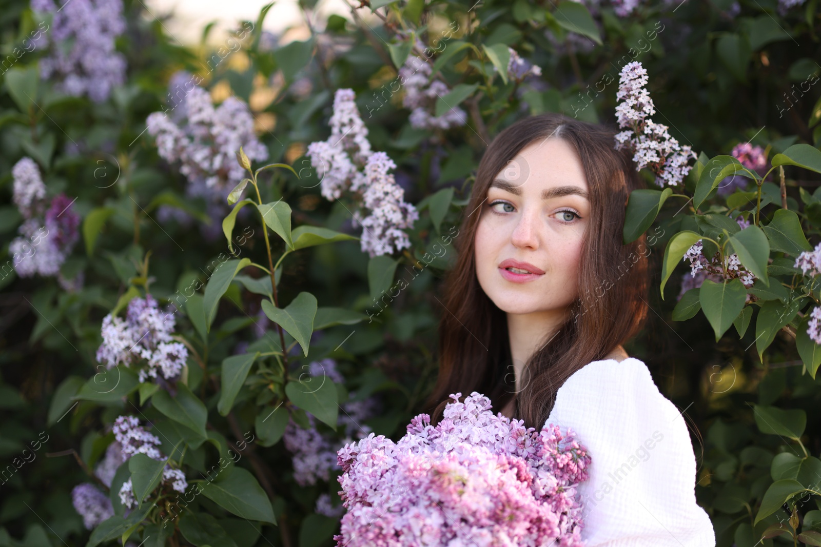 Beautiful woman among lilac flowers and leaves outdoors Photo of Beautiful woman among lilac flowers and leaves outdoors