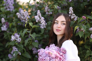 Photo of Beautiful woman among lilac flowers and leaves outdoors