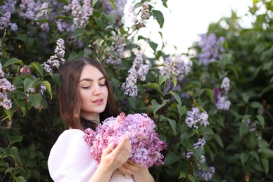 Photo of Beautiful woman among lilac flowers and leaves outdoors