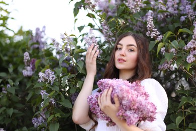 Photo of Beautiful woman among lilac flowers and leaves outdoors, low angle view