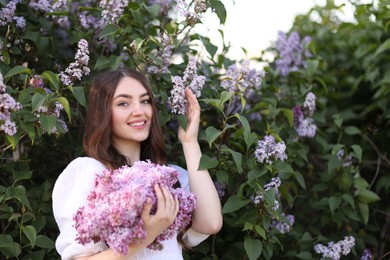 Photo of Smiling woman among lilac flowers and leaves outdoors