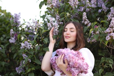 Photo of Smiling woman among lilac flowers and leaves outdoors