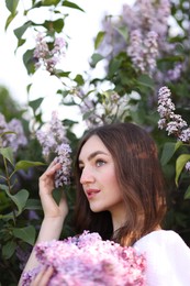 Photo of Beautiful woman among lilac flowers and leaves outdoors