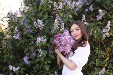 Photo of Beautiful woman among lilac flowers and leaves outdoors