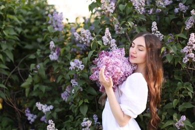 Photo of Beautiful woman among lilac flowers and leaves outdoors
