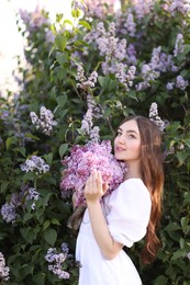 Photo of Smiling woman among lilac flowers and leaves outdoors
