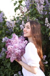Photo of Smiling woman among lilac flowers and leaves outdoors