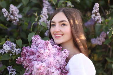 Photo of Smiling woman among lilac flowers and leaves outdoors