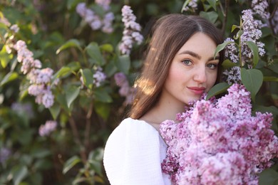 Photo of Beautiful woman among lilac flowers and leaves outdoors