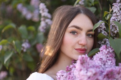 Photo of Beautiful woman among lilac flowers and leaves outdoors, closeup