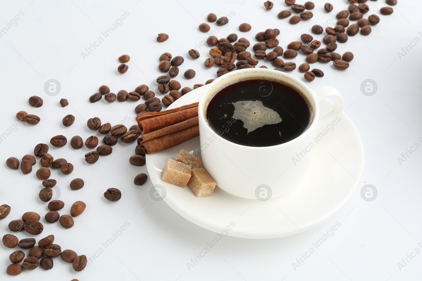 Aromatic coffee in cup, beans, cinnamon and sugar cubes isolated on white Photo of Aromatic coffee in cup, beans, cinnamon and sugar cubes isolated on white