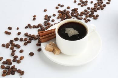 Photo of Aromatic coffee in cup, beans, cinnamon and sugar cubes isolated on white