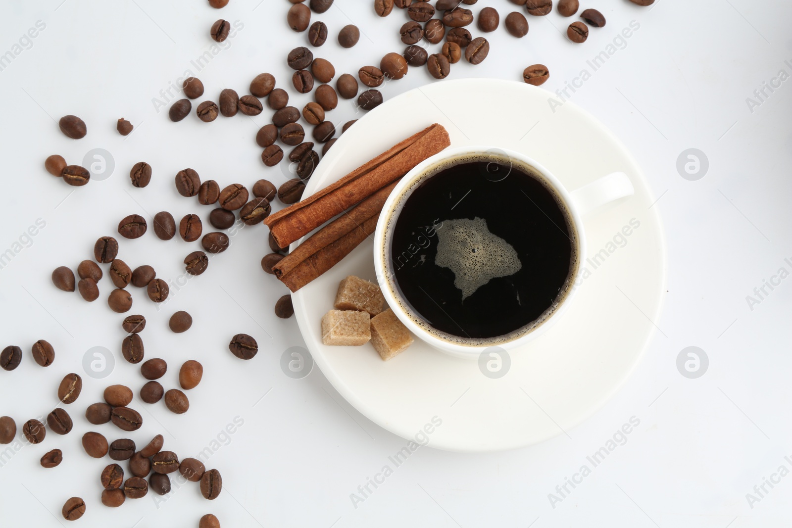 Aromatic coffee in cup, beans, cinnamon and sugar cubes isolated on white, top view Photo of Aromatic coffee in cup, beans, cinnamon and sugar cubes isolated on white, top view
