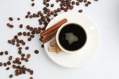 Photo of Aromatic coffee in cup, beans, cinnamon and sugar cubes isolated on white, top view