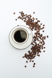 Photo of Aromatic coffee in cup and beans on white background, top view