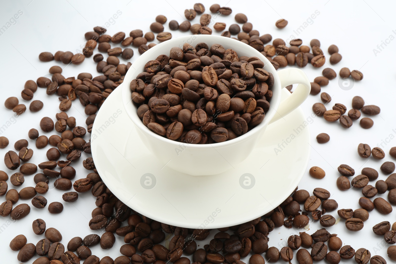 Aromatic coffee beans and cup on white background, closeup Photo of Aromatic coffee beans and cup on white background, closeup