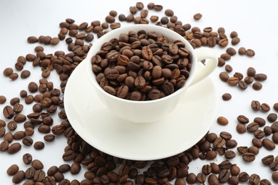 Photo of Aromatic coffee beans and cup on white background, closeup