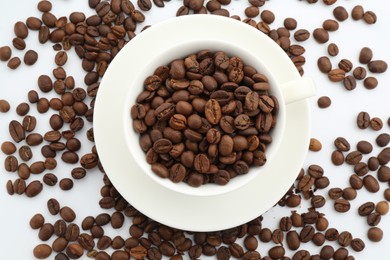Photo of Aromatic coffee beans and cup on white background, flat lay