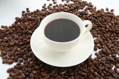 Photo of Aromatic coffee in cup and beans on white background, closeup
