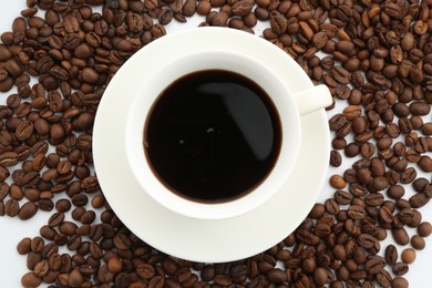 Photo of Aromatic coffee in cup and beans on white background, flat lay