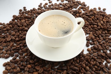 Photo of Aromatic coffee in cup and beans on white background, closeup