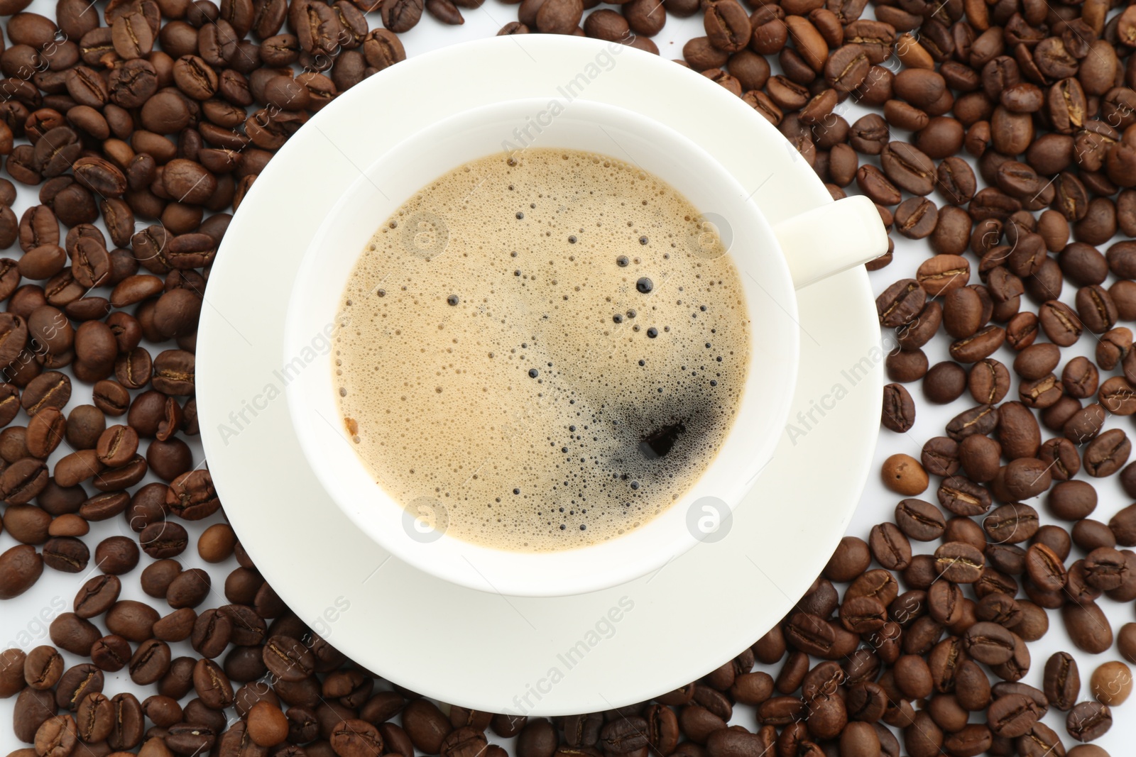 Aromatic coffee in cup and beans on white background, flat lay Photo of Aromatic coffee in cup and beans on white background, flat lay