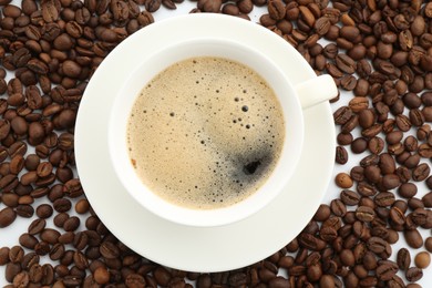 Photo of Aromatic coffee in cup and beans on white background, flat lay