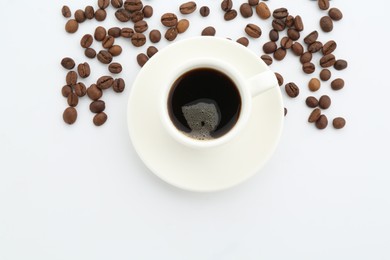 Photo of Aromatic coffee in cup and beans on white background, top view