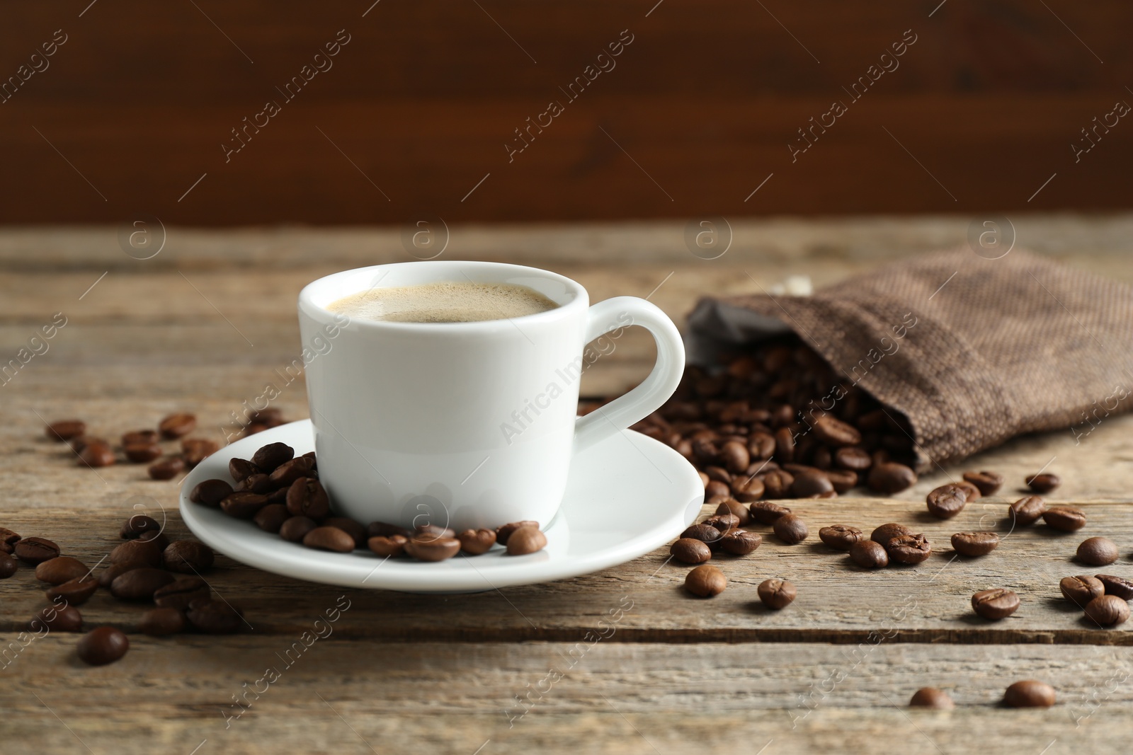 Aromatic coffee in cup and beans on wooden table, closeup Photo of Aromatic coffee in cup and beans on wooden table, closeup