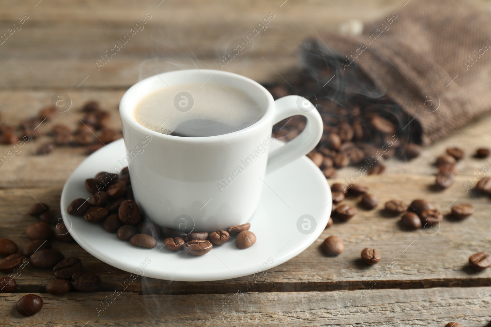 Aromatic coffee in cup and beans on wooden table, closeup Photo of Aromatic coffee in cup and beans on wooden table, closeup