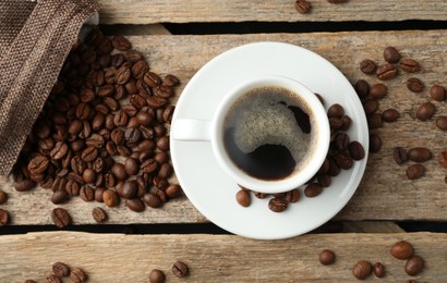 Photo of Aromatic coffee in cup and beans on wooden table, flat lay