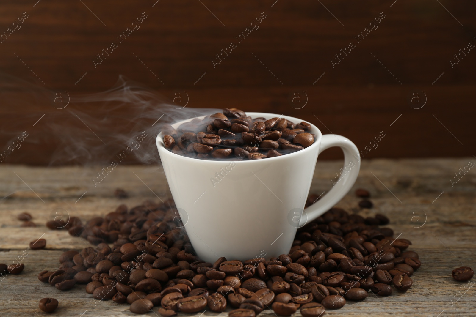 Aromatic coffee beans and cup on wooden table, closeup Photo of Aromatic coffee beans and cup on wooden table, closeup