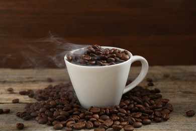 Photo of Aromatic coffee beans and cup on wooden table, closeup