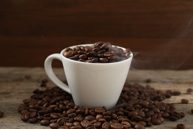Photo of Aromatic coffee beans and cup on wooden table, closeup