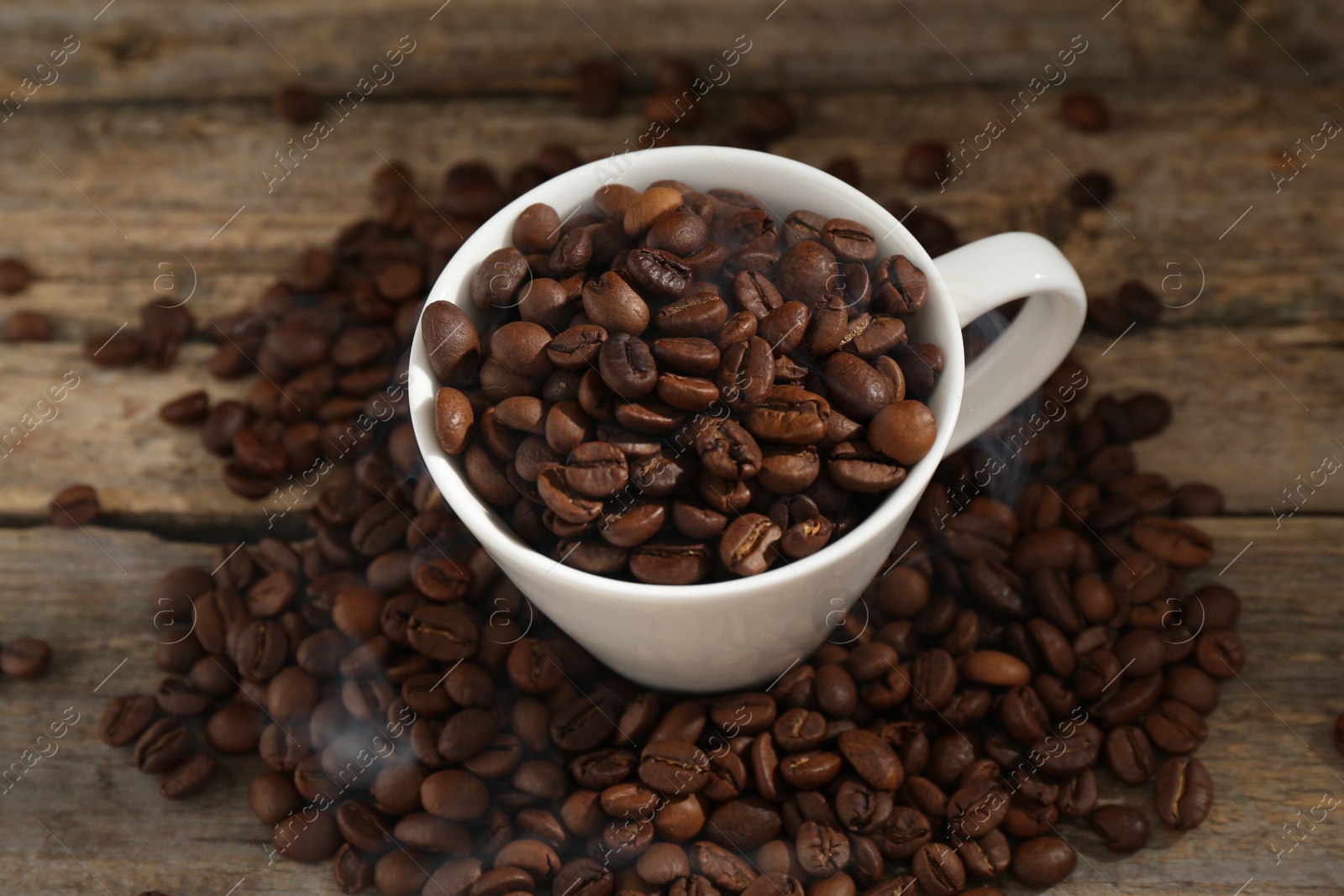 Aromatic coffee beans and cup on wooden table, above view Photo of Aromatic coffee beans and cup on wooden table, above view