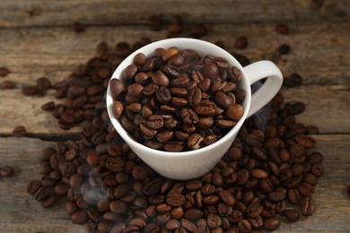 Photo of Aromatic coffee beans and cup on wooden table, above view