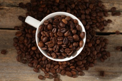 Photo of Aromatic coffee beans and cup on wooden table, flat lay