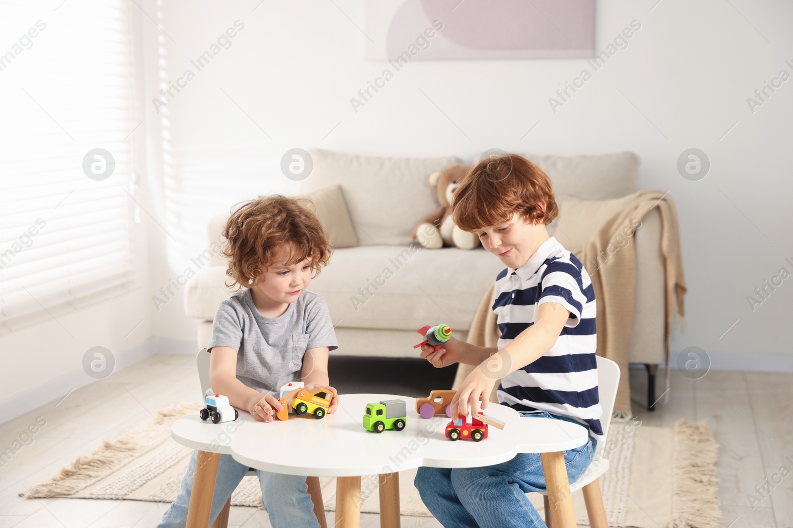 Cute little brothers playing with toys at table indoors Photo of Cute little brothers playing with toys at table indoors