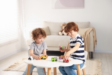Photo of Cute little brothers playing with toys at table indoors