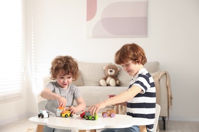 Photo of Cute little brothers playing with toys at table indoors