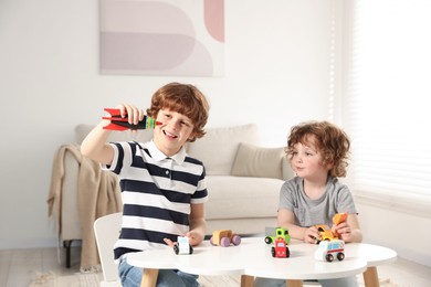 Photo of Cute little brothers playing with toys at table indoors