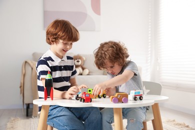 Photo of Cute little brothers playing with toys at table indoors