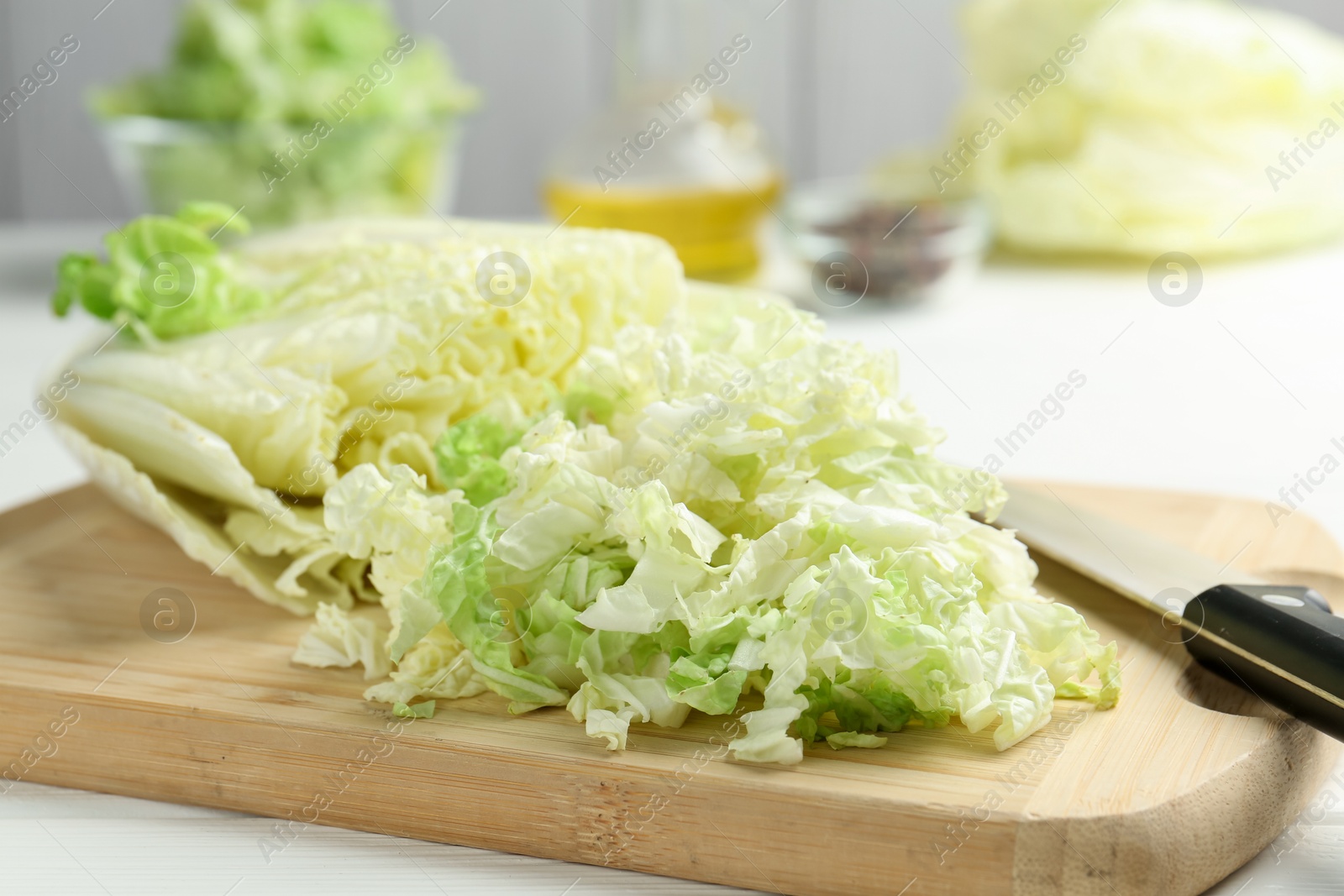 Photo of Cut Chinese cabbage and knife on white wooden table, closeup