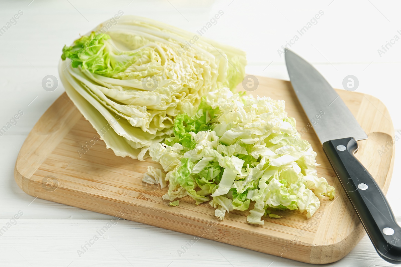 Photo of Cut Chinese cabbage and knife on white wooden table, closeup